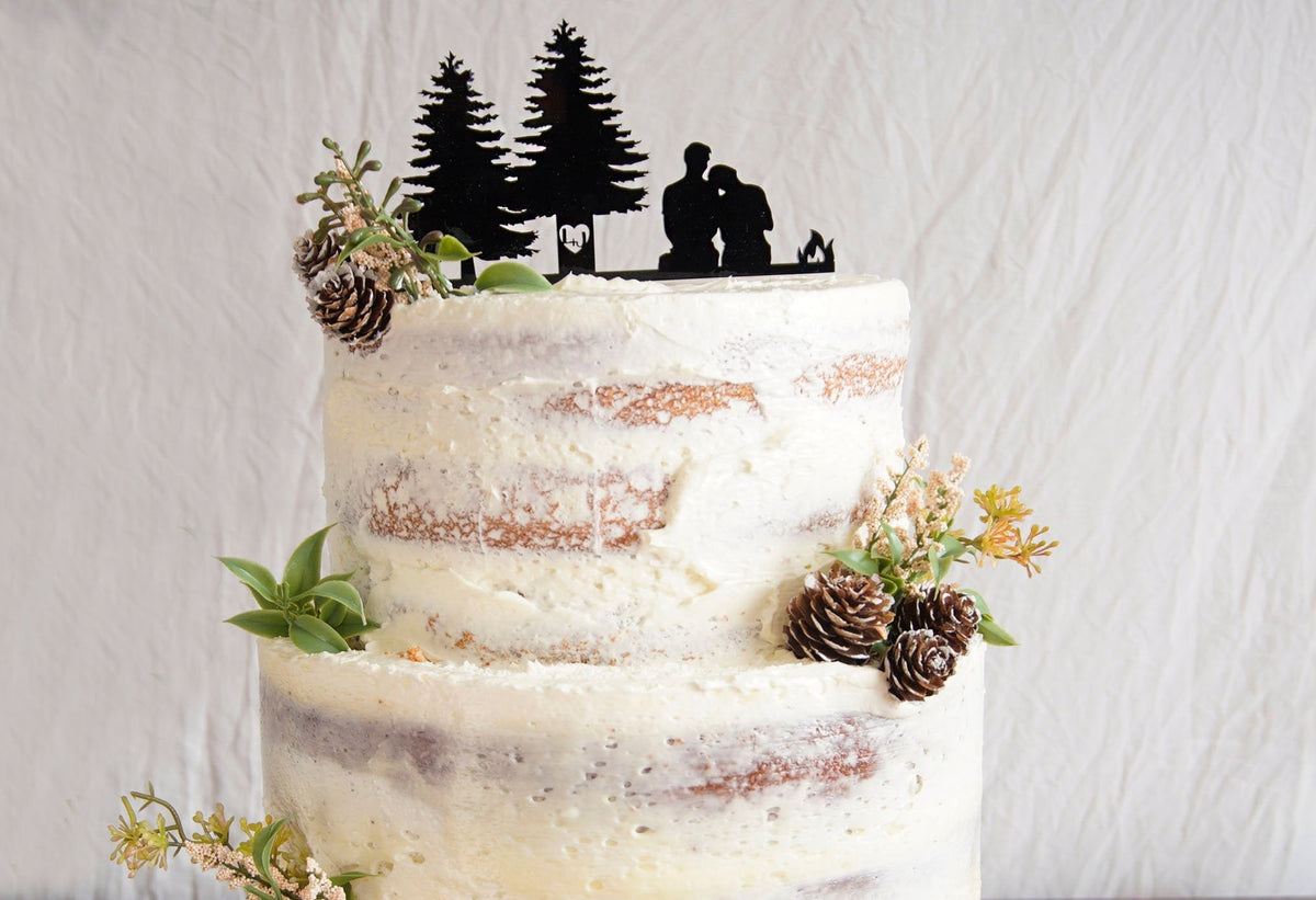 Rustic Wedding Cake Topper and Wedding Decor. Man + Woman Sitting Near Campfire and 2 Trees with the the couples initials cut/carved into the trees. Can be personalized and customized with pets and Mountain Ranges.